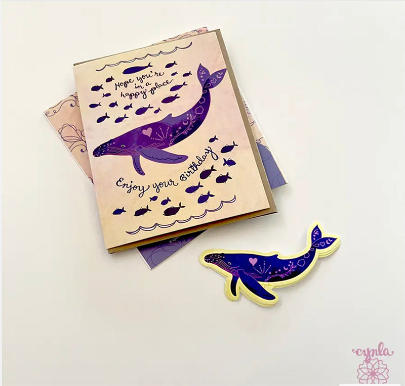 Greeting card with purple whale design and matching sticker on a white background